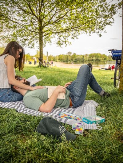 Couple d'amoureux en week-end à Rennes allongés sur l'herbe au bord de l'eau avec des vélos