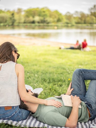 Un couple fait la sieste et bouquine aux étangs d'Apigné avec en arrière-plan un vélo star.