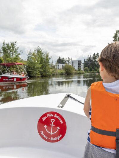 Un enfant fait un signe à un autre bateau électrique sur le canal