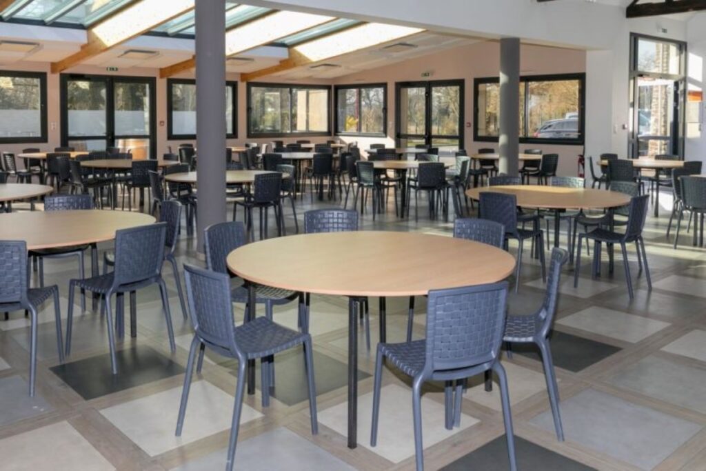 Grande salle de réception du gîte, avec tables rondes et chaises