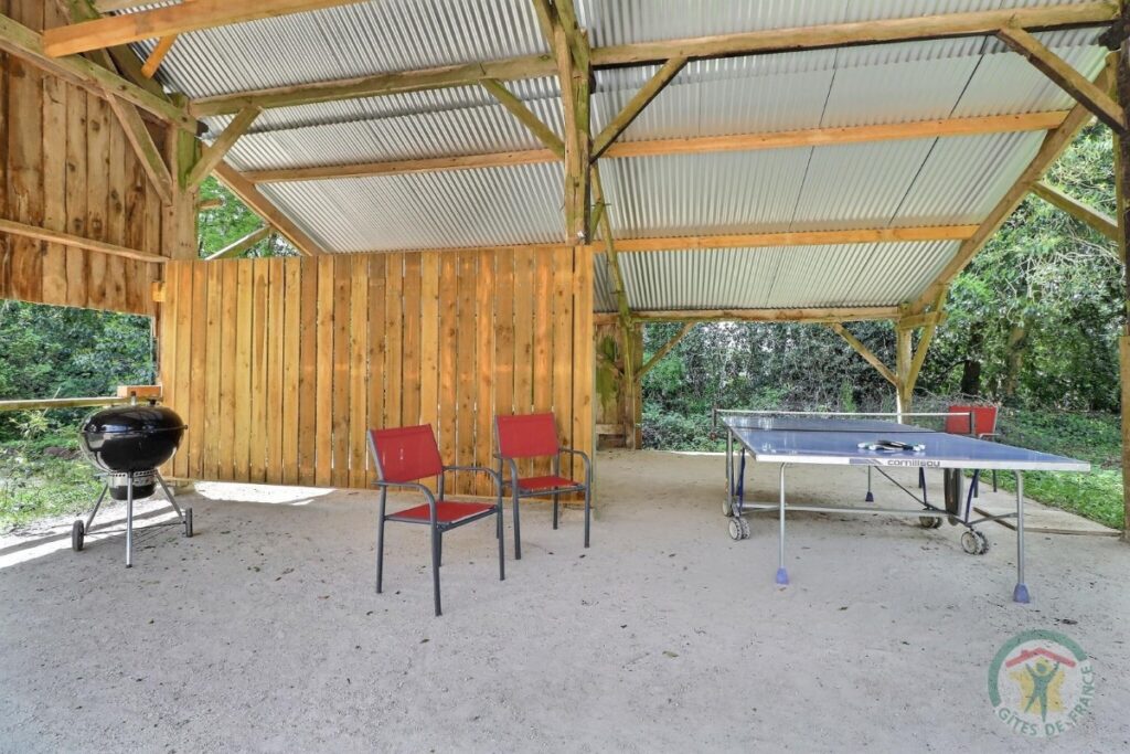 Table de ping-pong, chaises et barbecue sous terrasse couverte