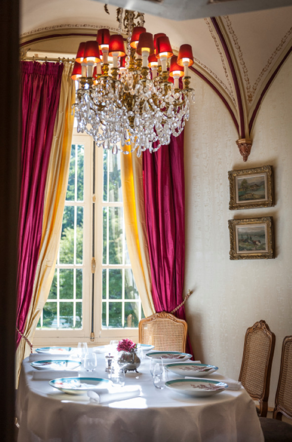 table de six couverts sous un lustre et à côté d'une fenêtre