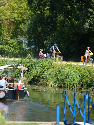 Cyclistes sur le halage et bateau sur la rivière.