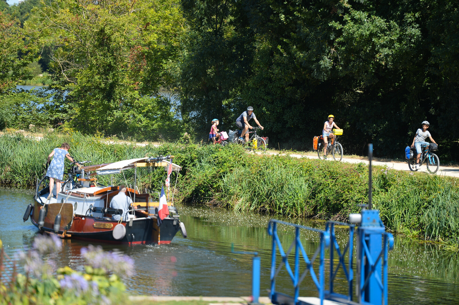 Cyclistes sur le halage et bateau sur la rivière.