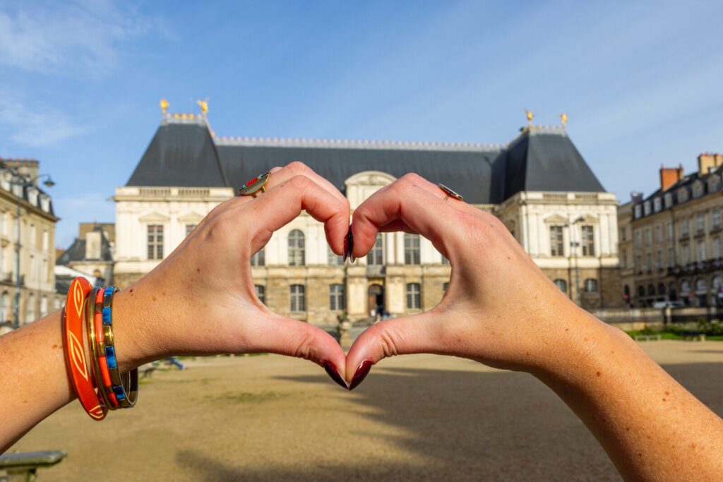 Une visiteuse fait un coeur avec ses doigts devant la place du Parlement de Bretagne