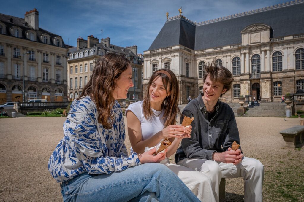 Trois étudiants dégustent des galettes saucisse devant le Parlement