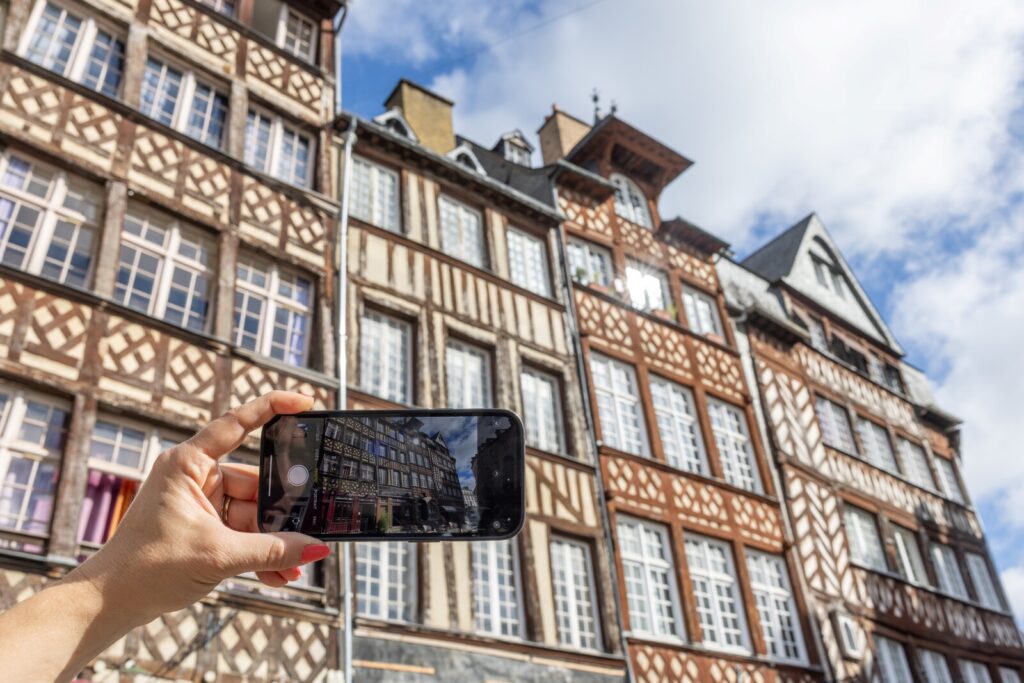 Personne prenant une photo des maisons à pan de bois avec son téléphone