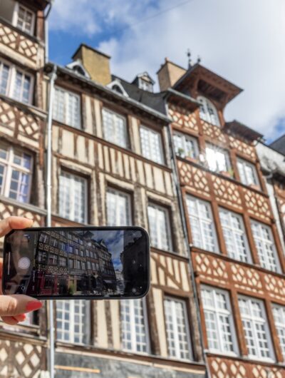 Personne prenant une photo des maisons à pan de bois avec son téléphone
