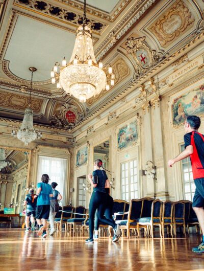 Coureurs à pied qui traversent la salle des mariages de la mairie à l'occasion du Rennes Urban Trail