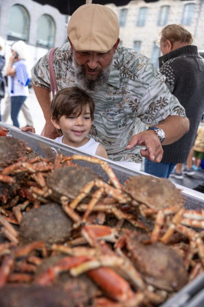 Un père et son fils regardent des araignées de mer sur un étal du marché des lices à Rennes en Bretagne