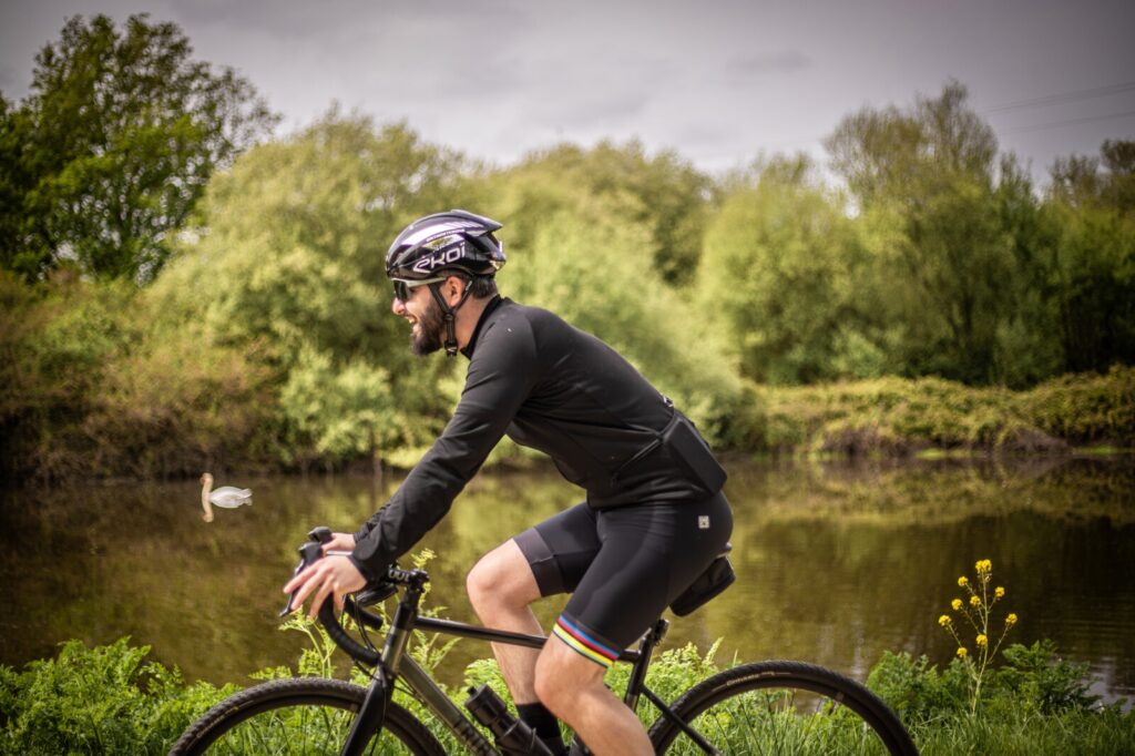 Cycliste visiblement très heureux de pédaler au bord du halage du côté d'Apigné à Rennes. En arrière-plan un cygne prend son temps tranquillement.