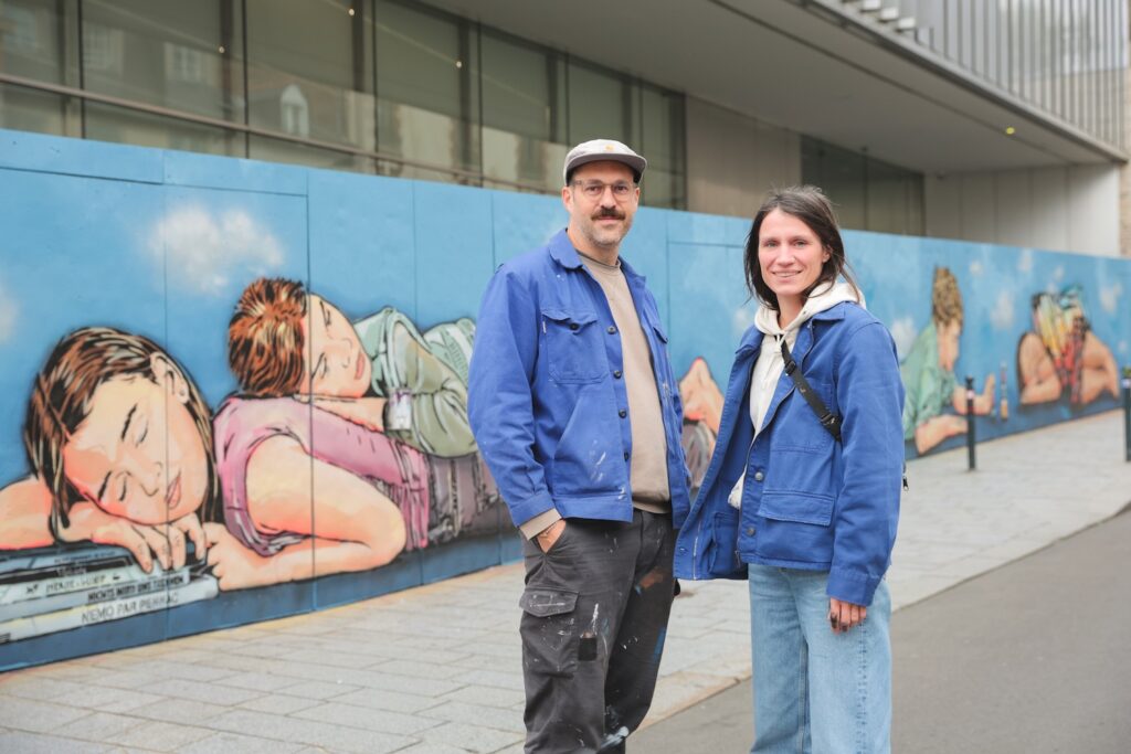 Le duo d'artistes Jana & JS devant leur fresque réalisée en octobre 2025 à l'occasion des Journées nationales de médecine périnatale qui ont lieu au Couvent des Jacobins.
