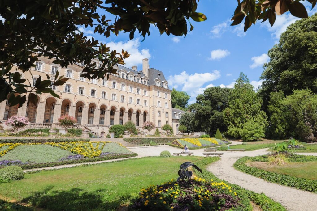 Vue du jardin Saint-Georges et du Palais en été avec des parterres fleuris.