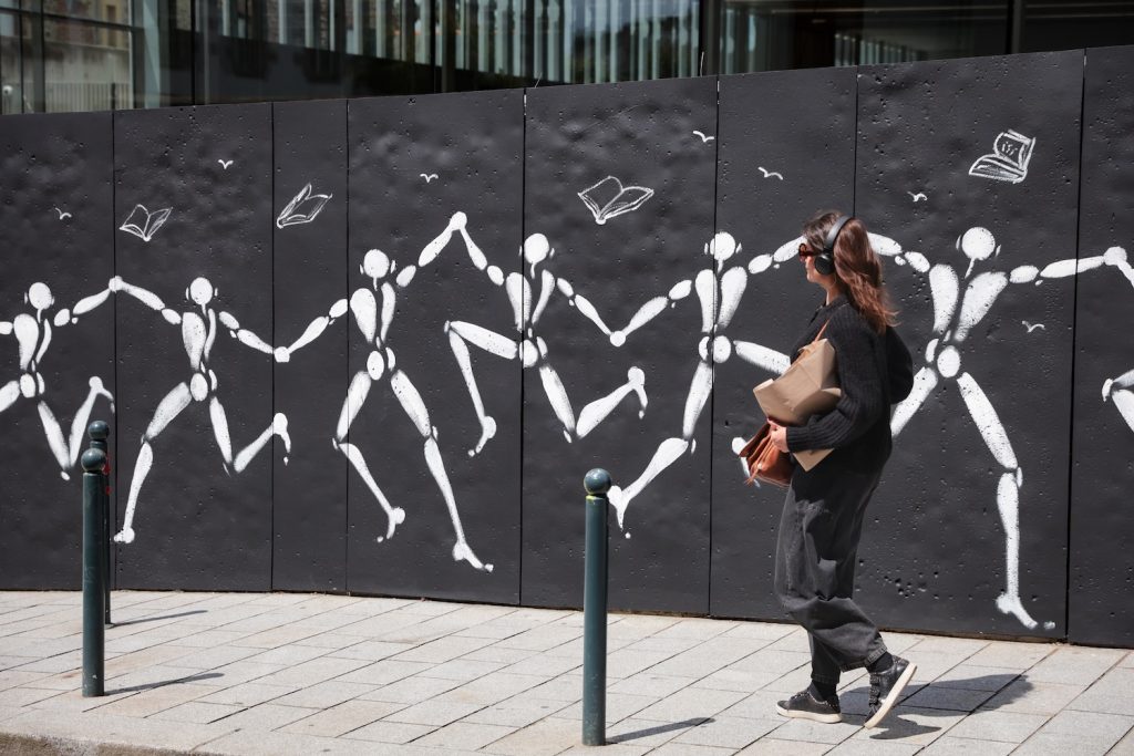 Une femme passe devant la fresque de l'artiste urbain Jérôme Mesnager à Rennes.
