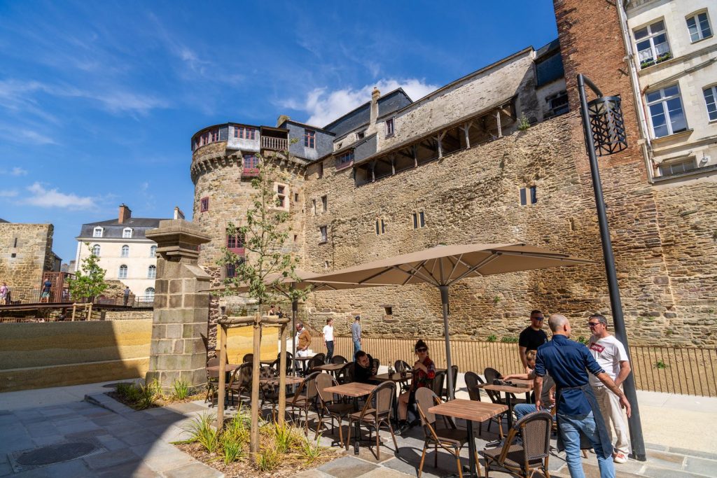 Terrasse d'un restaurant sous le soleil avec vue sur les remparts et la Porte Mordelaise