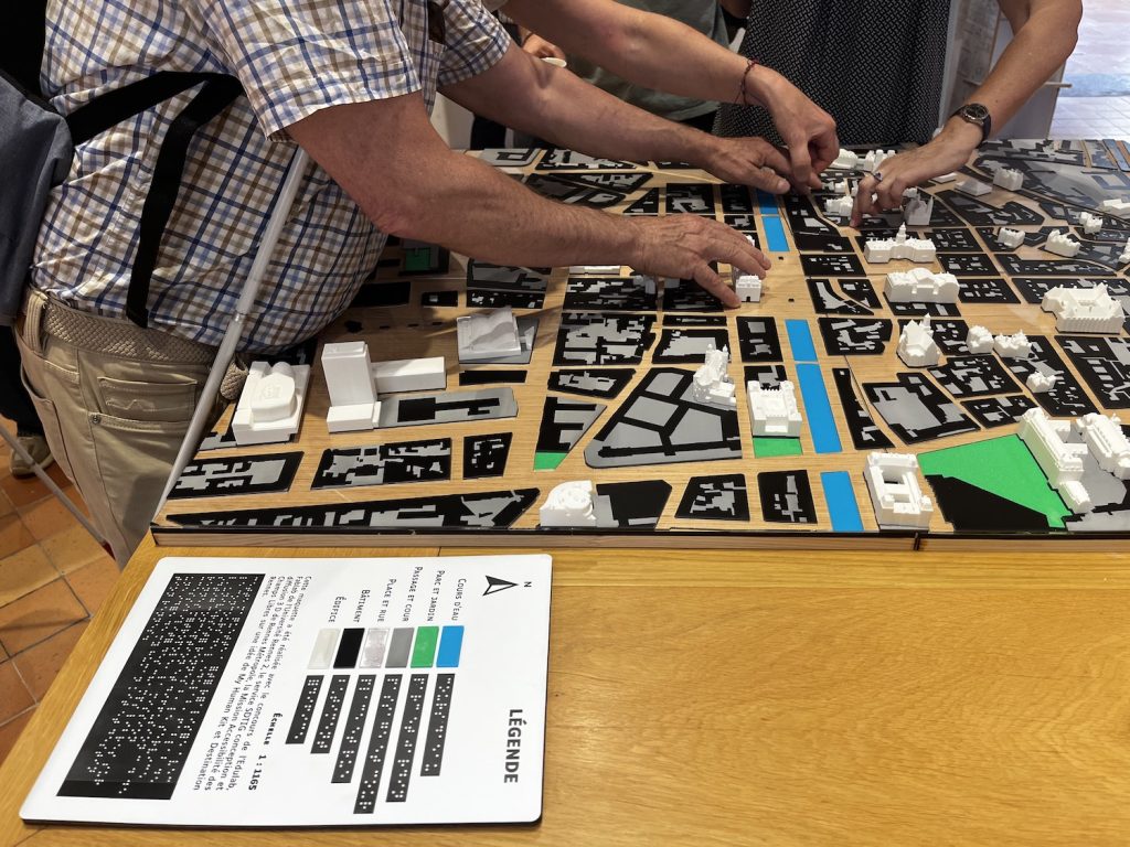 Une personne malvoyante touche la maquette 3D installée à l'office de tourisme