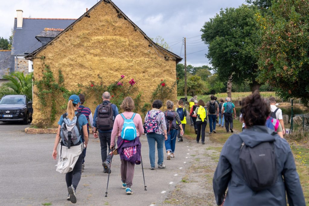 Randonnée patrimoniale entre Acigné et Thorigné, un groupe de marcheurs passe devant une maison typique en bauge.