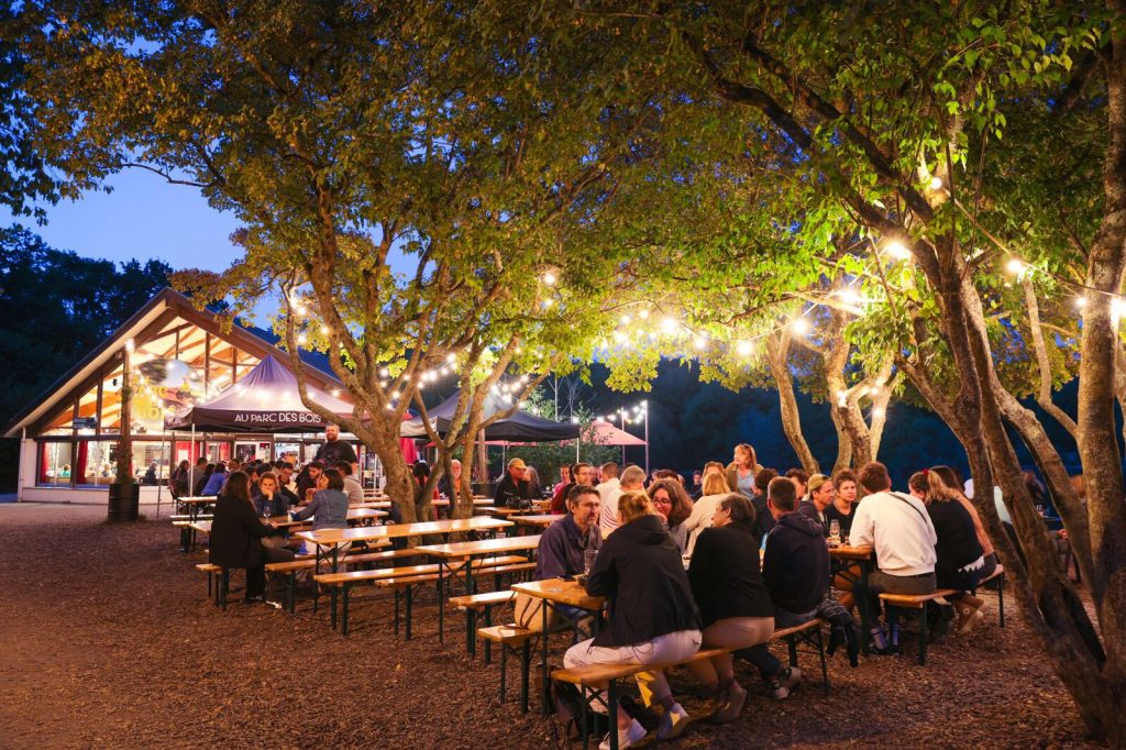 Des personnes dînent le soir à la guinguette du Parc des Bois
